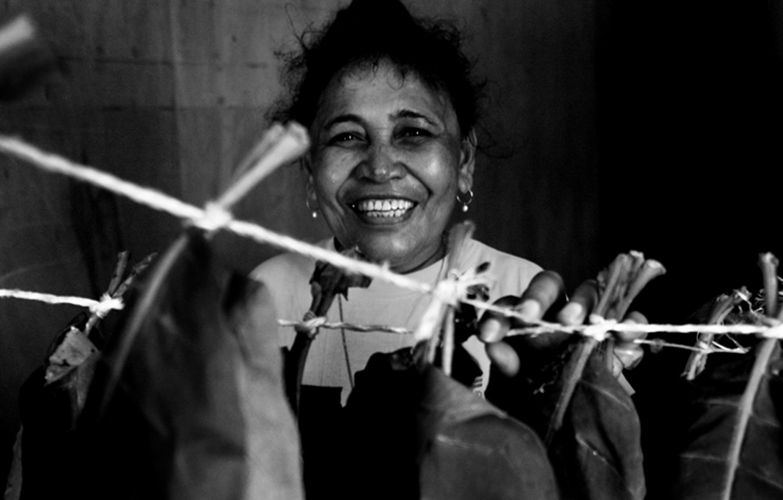 Tabac - Outre les cultures vivrières, les Wallisiens et Futuniens plantent aussi du tabac qu’ils font sécher et préparent avant de le fumer. Ici, Thérèse pose devant les plants de tabac qui sèchent dans une pièce de sa maison, au squat de Sakamoto.