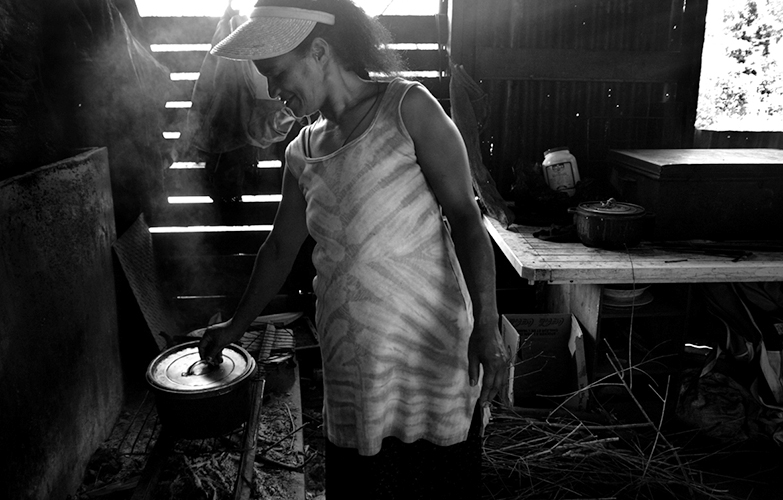 Hospitalité - Originaire de Houailou, Evelyne vit au squat de Yelos depuis 1997. En saison fraîche, elle plante du manioc, des patates. Elle était méfiante la première fois qu’elle m’a vue avec l’appareil. ”D’abord, t’es qui toi?” Et puis là finalement, c’est café, crêpes de bananes et causerie. On se pose avec ses filles, Mélissandre, 12 ans, et Aurore, 1 ans. Francisca, la jumelle de Mélissandre, se cache. On lui a coupé les cheveux ce matin et elle boude. 