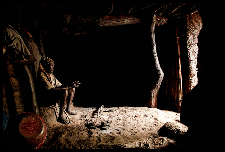 Diene Ndah, à l’intérieur de son Tata. Tous ses enfants sont scarifiés. Sa femme, Kanti Kouabo, porte une croix autour du cou et allie  - comme de nombreux Béninois - culte animiste et religion catholique. “Quand on va à l’église, dans toute prière, on parle de Dieu. Et sur les fétiches, quand on demande quelque chose on parle aussi de Dieu. Tout est lié”.