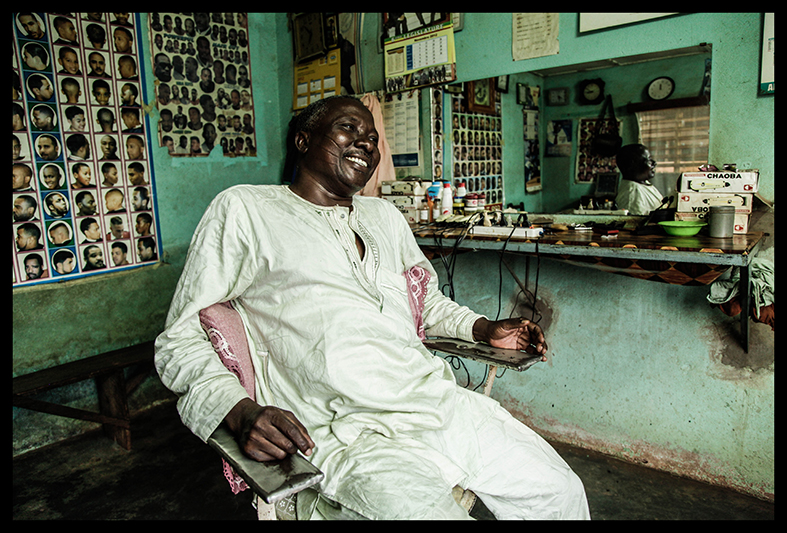 Moustapha Ganiou, dans son salon de coiffure de Natitingou. “Ce que j’ai sur les joues là, ça montre mon ethnie, que je suis Yoruba. Et je suis fier d’être Yoruba. Je suis à l’aise avec ça dans ma peau! Mes enfants? Non, ils ne portent pas ça. Je n’ai pas choisi cela pour eux, parce qu’aujourd'hui, le monde a évolué.”