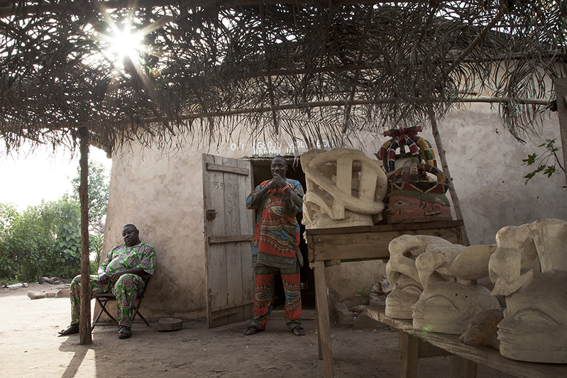 Bernardin Adebayo sculpte des masques Guèlèdè depuis plus de trois décennies. Sur ses masques, des paraboles animalières ou des symboles de pourvoir. Le sculpteur est aussi danseur de Guèlèdè, et manie l''akpala', ce pipeau qui marque le début des danses nocturnes. Ofia, Bénin, 2017. ©Laeïla Adjovi 