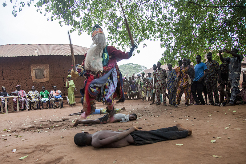 Pour marquer sa puissance et amuser la galerie, Elegbara fait coucher au sol certains des plus jeunes spectateurs. Ofia, Bénin, 2017. ©Laeïla Adjovi 