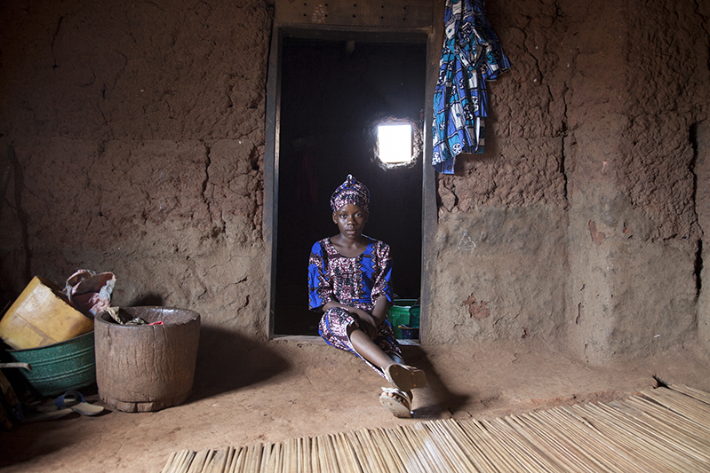 Adjima Sande, agée de 12 ans, a déjà joué le rôle d''Arugba' à cinq reprises. Lors de la danse Guèlèdè, 'Arugba', qui signifie 'porteuse de calebasse' en Yoruba, est une jeune vierge désignée dans la famille des danseurs. Elle arrive en éclaireur juste avant la sortie d'Efe, le masque le plus important. La calebasse fermée qu'elle porte sur la tête symbolise la puissance d'Awon Iya. Ofia, Bénin, 2017. ©Laeïla Adjovi