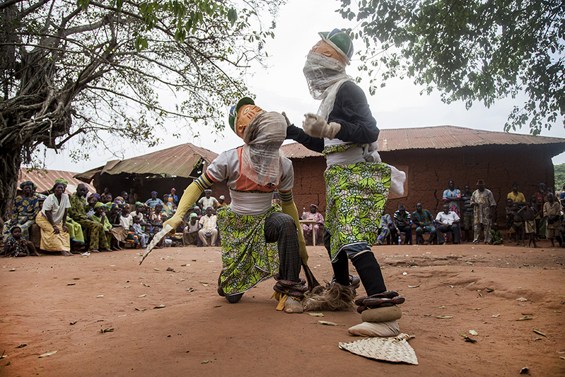 Des danseurs Guèlèdè portant des masques masculins poursuivent la danse 